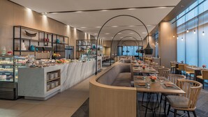 A modern restaurant with a marble counter, wooden seating, and large windows.