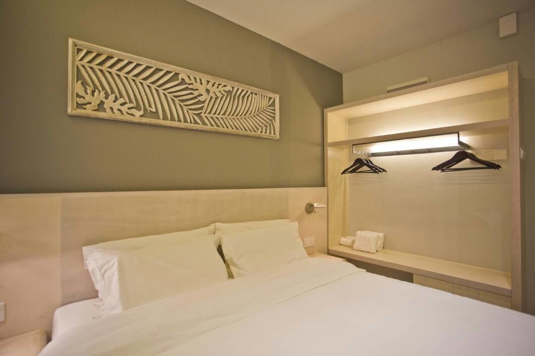 Une chambre d’hôtel avec un lit, un miroir avec un éclairage intégré et un élément décoratif mural.