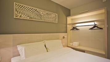 Une chambre d’hôtel avec un lit, un miroir avec un éclairage intégré et un élément décoratif mural.