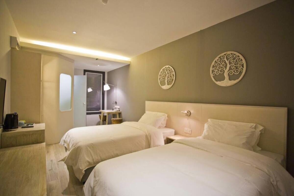 Ett hotellrum med två sängar, ett sängbord, en lampa och dekorativ väggkonst.