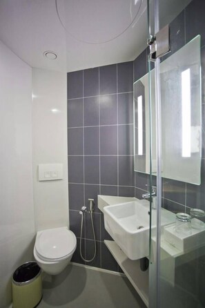 A modern bathroom with a toilet, bidet, and glass shower enclosure. - M+ Boutique Hotel (Gelang Patah)