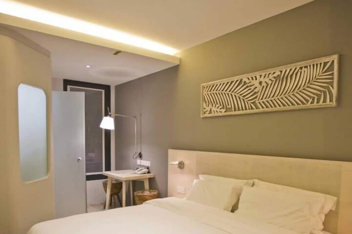 Ett modernt hotellrum med en stor säng, ett skrivbord med en stol och en dekorativ väggdekoration.