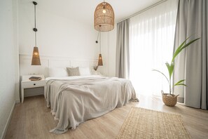 A bedroom with a bed, bedside tables, a hanging light fixture, a potted plant, and a window with curtains. - Sandal Alaçatı - Adults Only (Cesme)