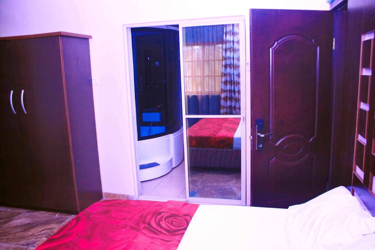 A bedroom with a bed, a wardrobe, a sliding glass door leading to a balcony, and a door to another room.