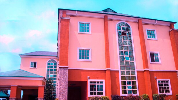 A large building with a prominent arched window and multiple smaller windows. - Agburuike Hotels (Aba)