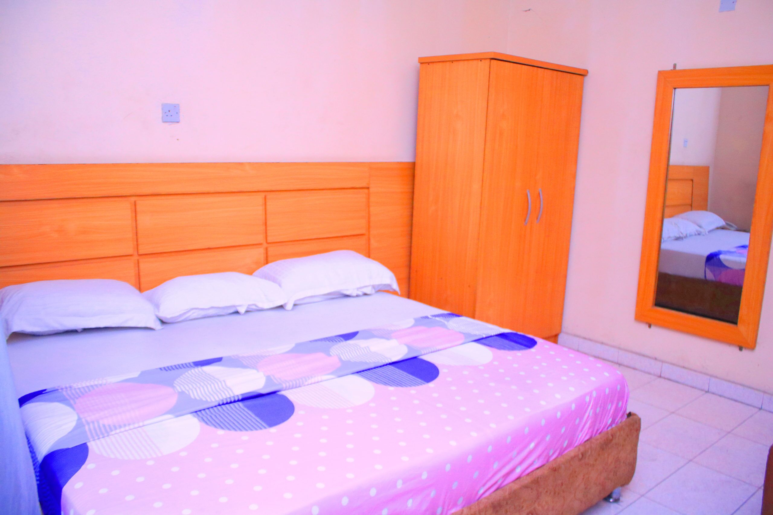 A bedroom with a bed, a wardrobe, and a mirror.