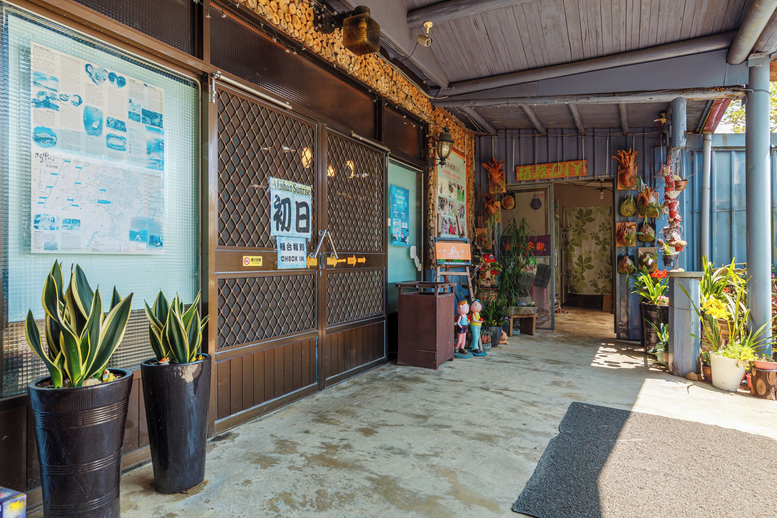 A storefront with a wooden exterior, a glass door with a sign, and potted plants outside.
