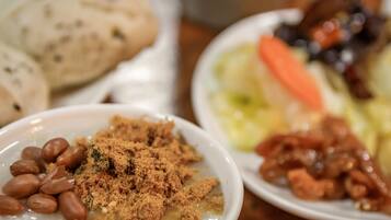 A table with various dishes including beans, a bowl of a crumbly substance, and a plate with vegetables and meat.