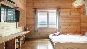 Una habitación de cabaña de madera con una cama, un escritorio y una ventana con cortinas.