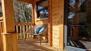 A wooden deck with a wicker chair and a window.