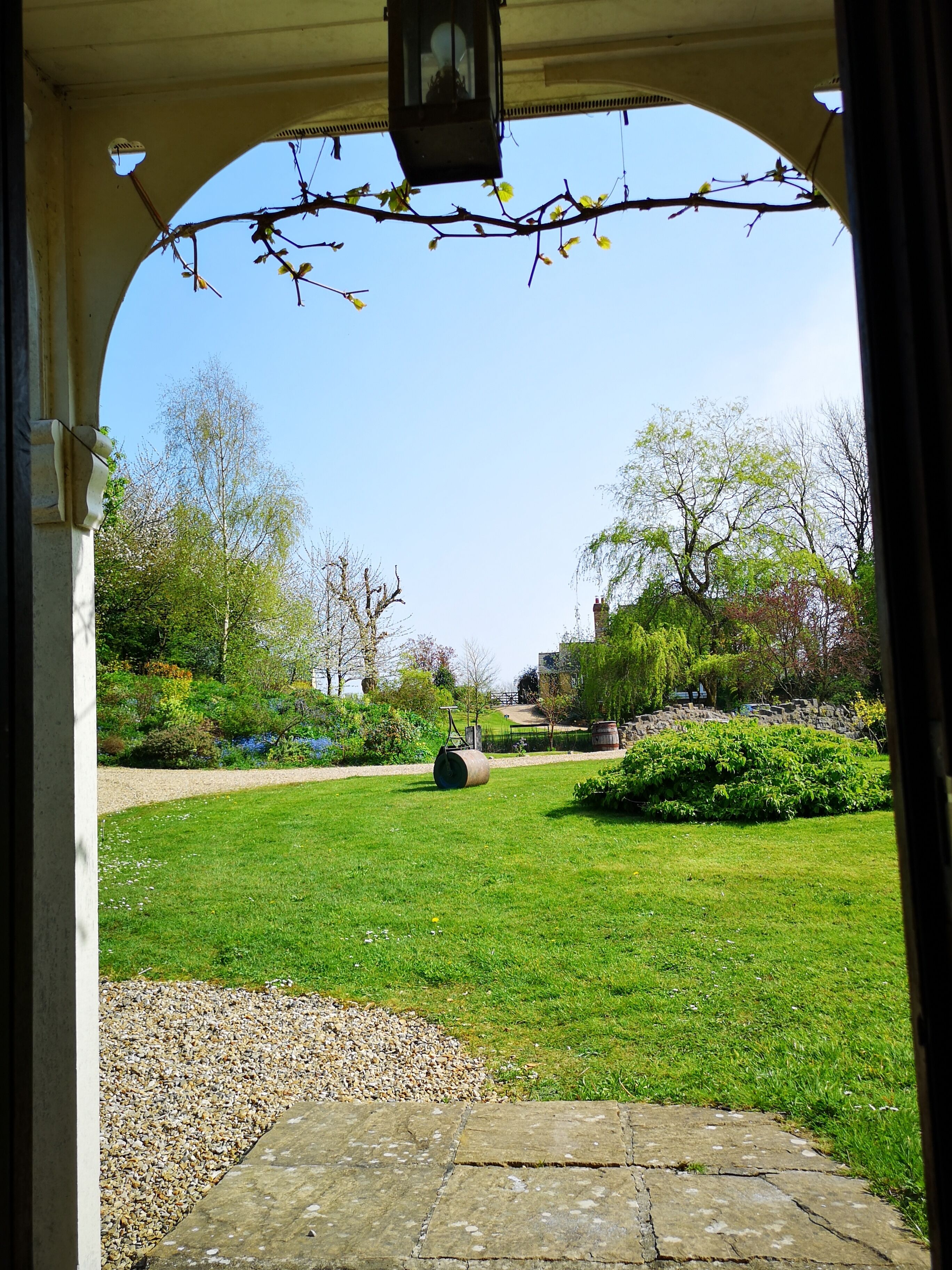 An outdoor garden area with a stone pathway, a lawn, and various plants and trees.
