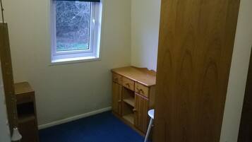 A small room with a window, a wooden cabinet, and a blue carpet.