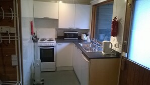 A compact kitchen with a stove, microwave, and sink. - Broxbourne Riverside Chalets (Broxbourne)