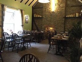 Un rincón comedor acogedor con paredes de piedra, muebles de madera y una chimenea de piedra.