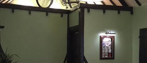 Un espace repas agrémenté de poutres en bois, d’un panneau indiquant la présence d’un local à vélos et d’un luminaire fixé au mur.