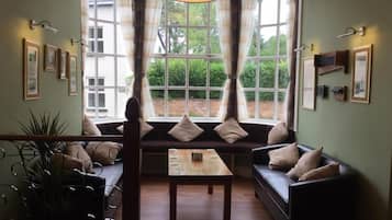Una habitación con un ventanal grande, un sofá, una mesa y una planta en maceta.