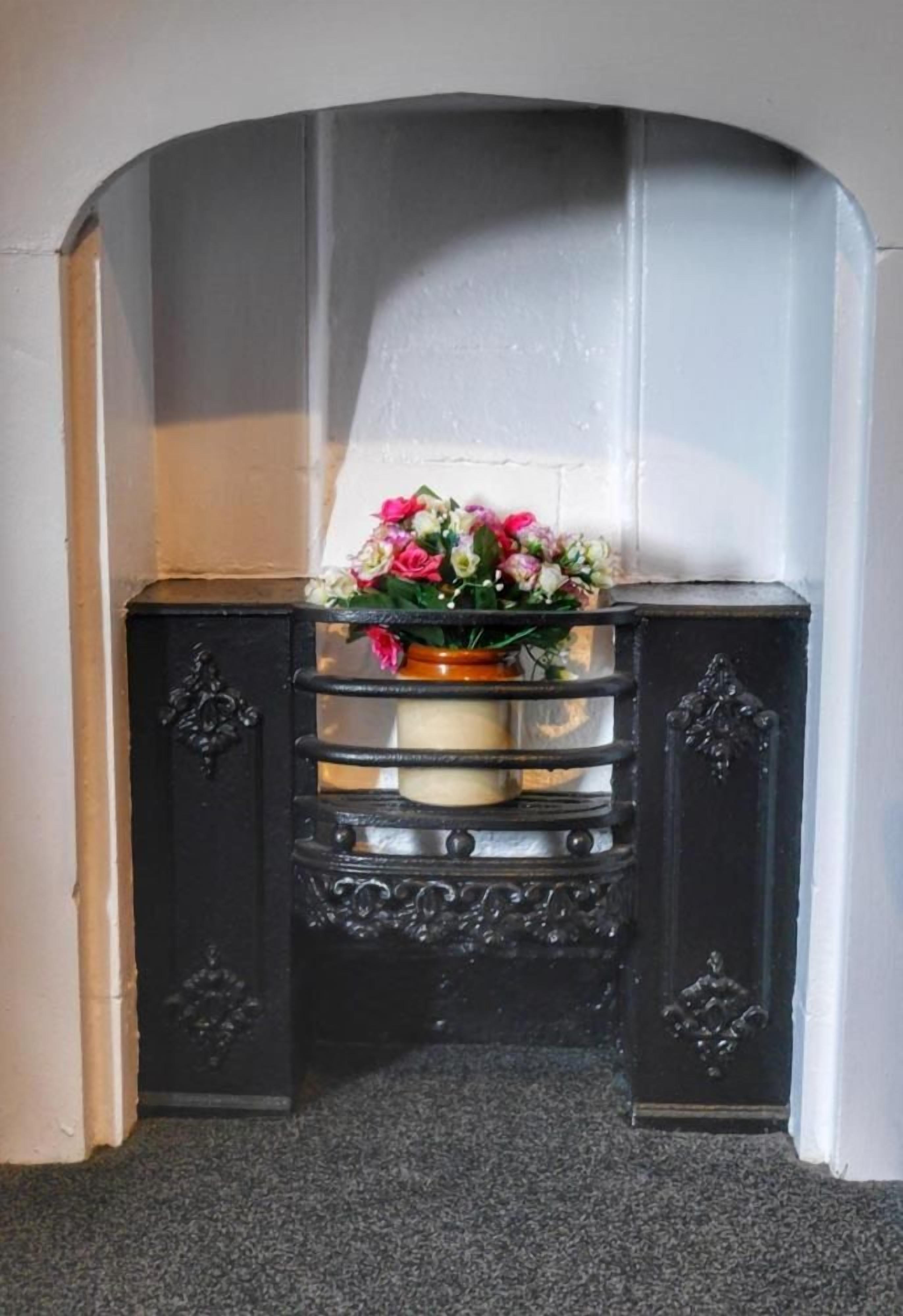 Eine schwarze Metallbank mit einem Blumenstrauß vor einer weißen Wand.