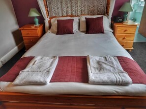 A neatly made bed with a patterned headboard, two bedside tables with lamps, and a red and white striped rug.