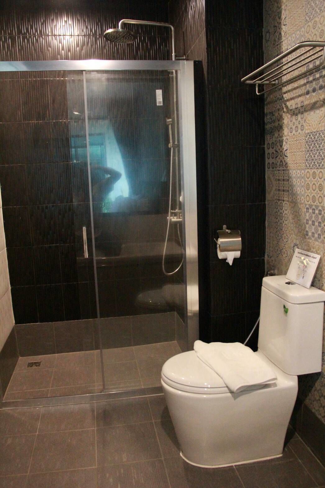 A modern bathroom with a glass-enclosed shower, a white toilet, and a towel rack.