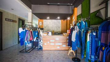 Una tienda de ropa con perchas llenas de prendas, un mostrador y un suelo con estampado.