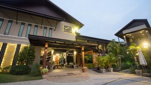 A modern hotel entrance with a covered outdoor area, potted plants, and a sign indicating the name of the hotel. - Anantaya Home Phare (Sung Men)