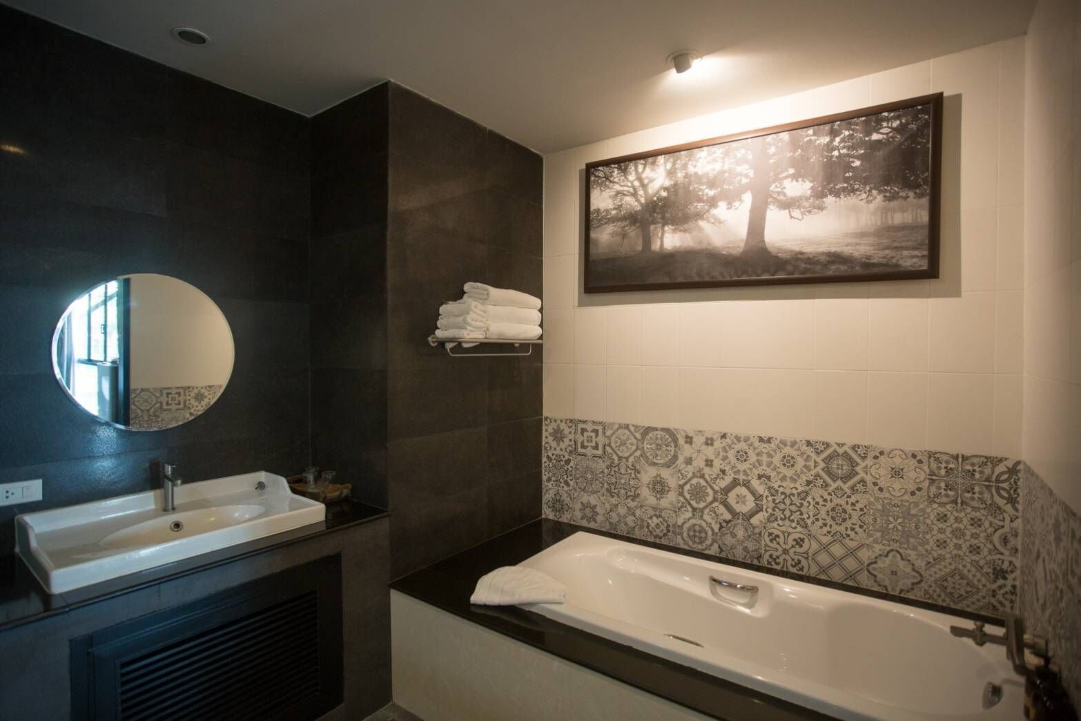 Um banheiro moderno com uma pia dupla, um espelho grande, uma banheira e um revestimento de parede decorativo.
