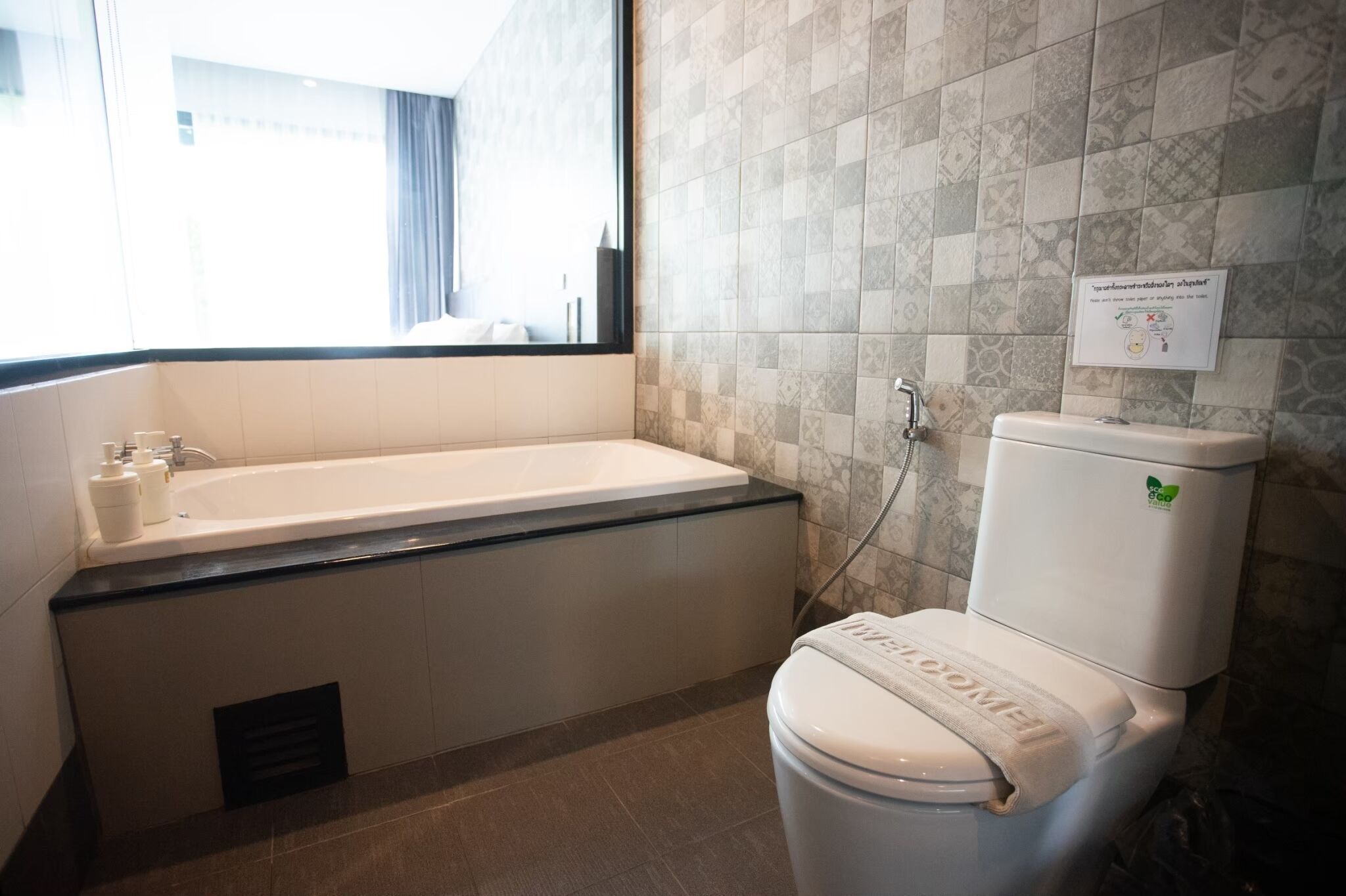 Un baño con bañera, inodoro y ventana.
