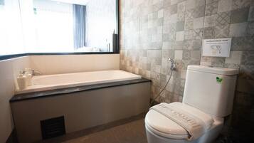Un baño con bañera, inodoro y ventana.