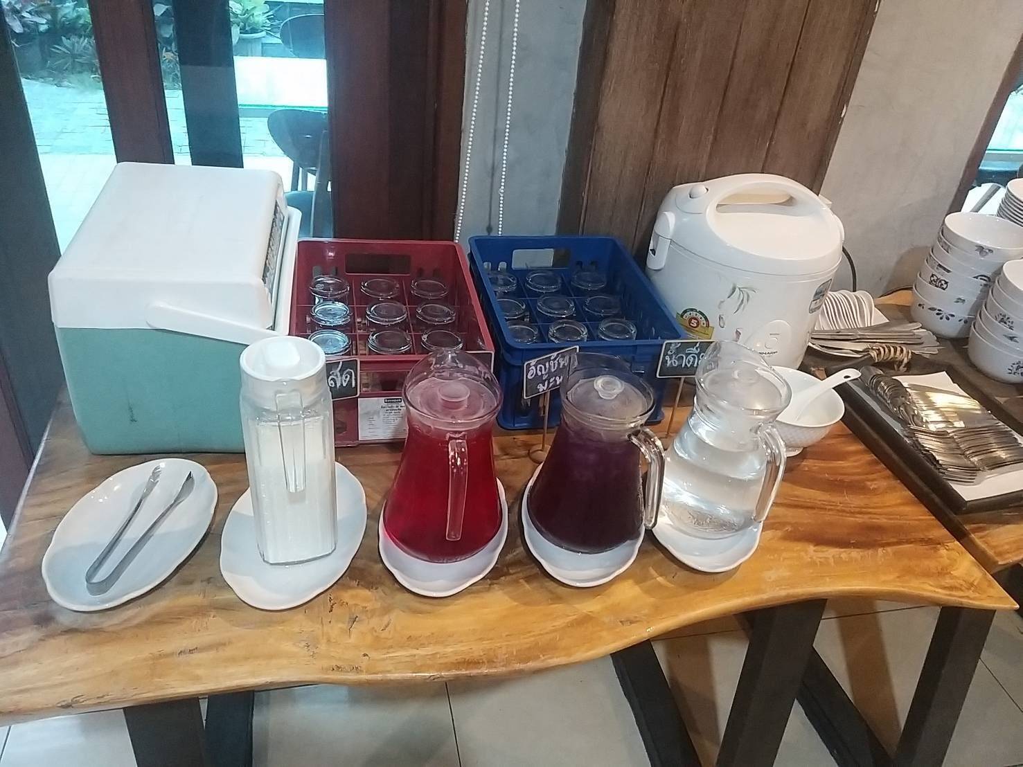 A table with various containers and utensils, including a blender, pitchers, and a food processor.