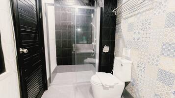 Un baño con ducha, inodoro y azulejos decorativos.