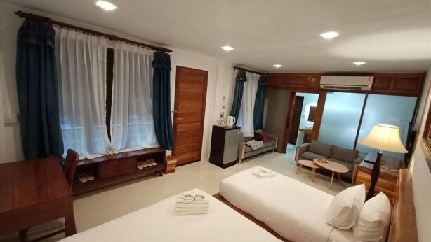A hotel room with two beds, a desk, a chair, a sofa, and a small table. - Anantaya Home Phare (Sung Men)