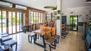 A modern restaurant with a wooden bar, large windows, and indoor plants. - Anantaya Home Phare (Sung Men)