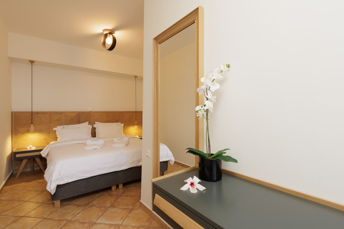 A hotel room with a bed, bedside table, nightstand, and a large mirror.