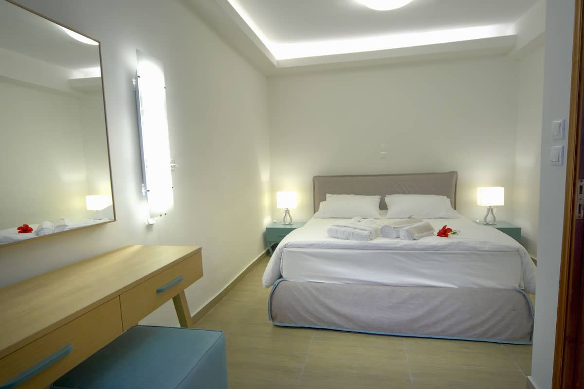 A hotel room with a bed, bedside tables, a mirror, and a desk.