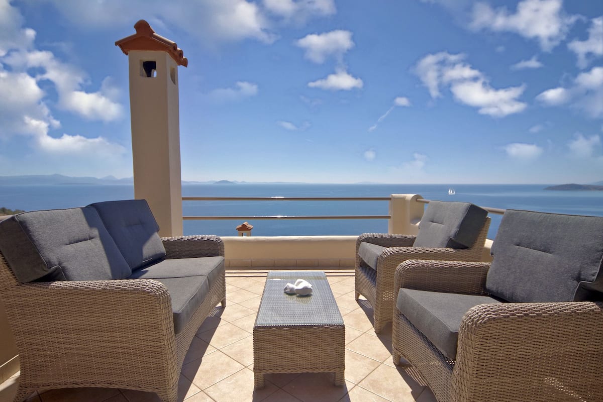 A balcony with wicker furniture and a view of the sea.