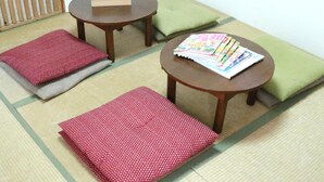 A tatami mat room with two low tables, cushions, and a box of tissues. - Harimayabashi Guest House - Hostel (Kochi)
