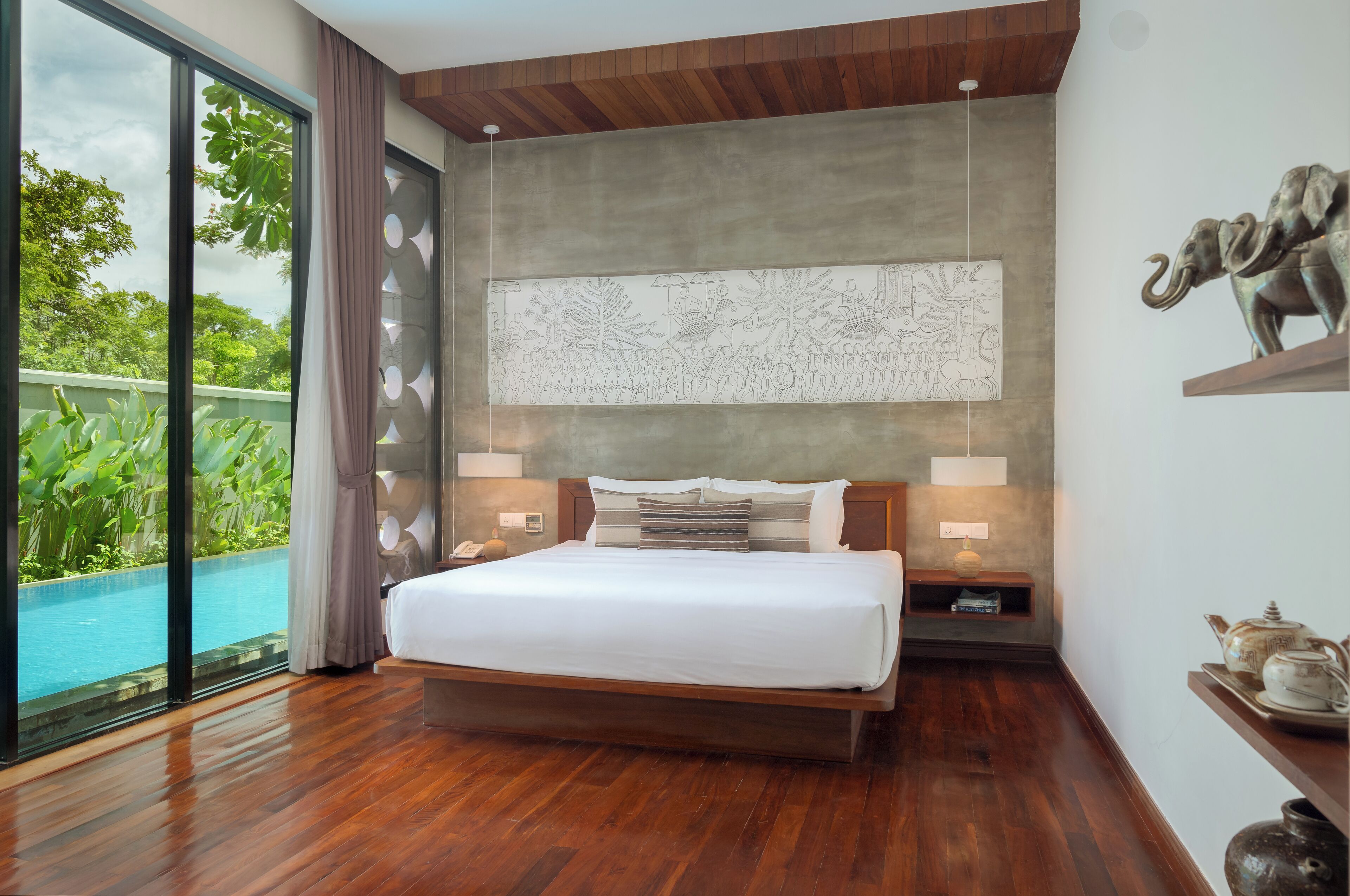 Un dormitorio moderno con una cama grande, suelo de madera, vista a una piscina y un cuadro abstracto de gran tamaño en la pared.