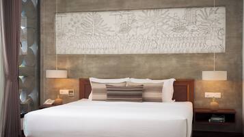 A hotel room with a large bed, two bedside tables with lamps, a wall-mounted artwork depicting a procession, and a window with a curtain.