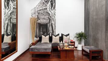 Uma sala de estar moderna com um grande quadro abstrato, lareira e um espaço de estar acolhedor com almofadas.
