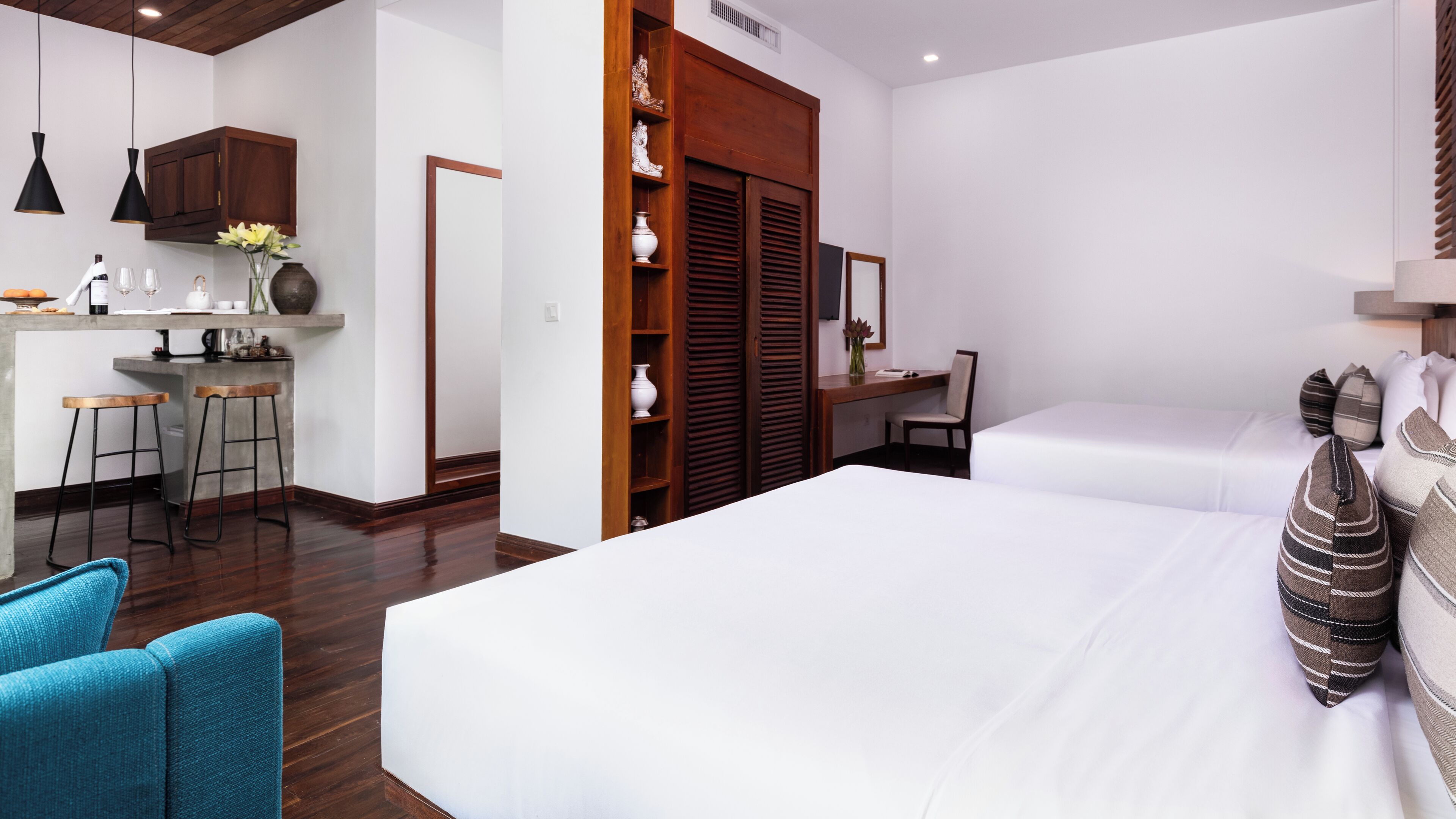 A hotel room with a bed, two chairs, a desk, and a kitchenette.