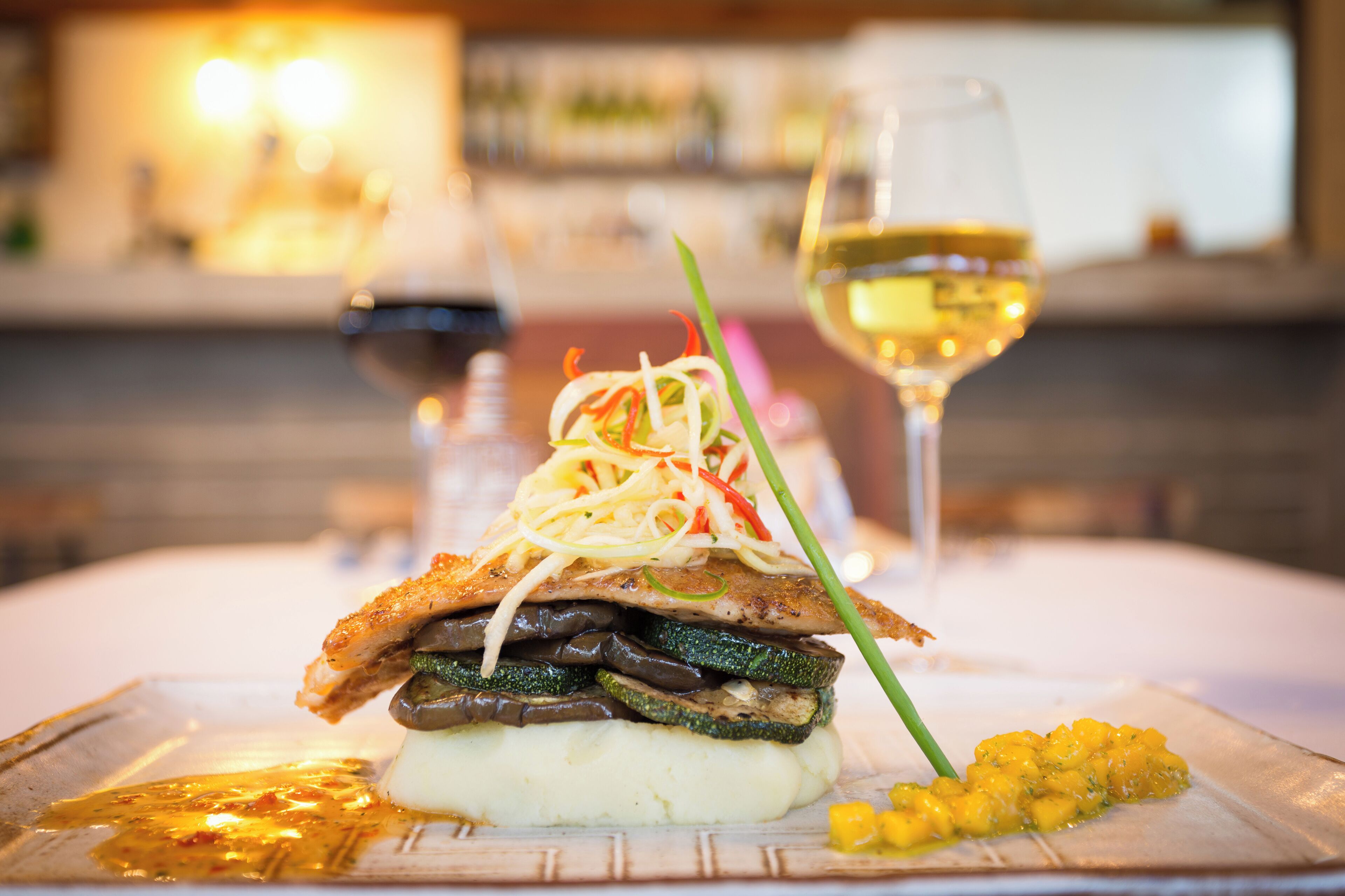 A plated dish with vegetables and a glass of white wine.