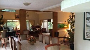 A dining area with a round table, chairs, and a Christmas tree. - The Garden Family Guest House (Ciawi)