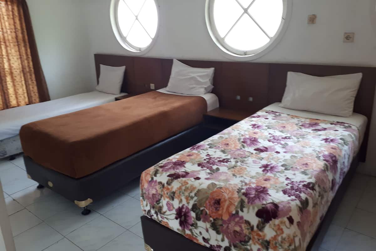 A hotel room with two single beds, a large window, and a small window.