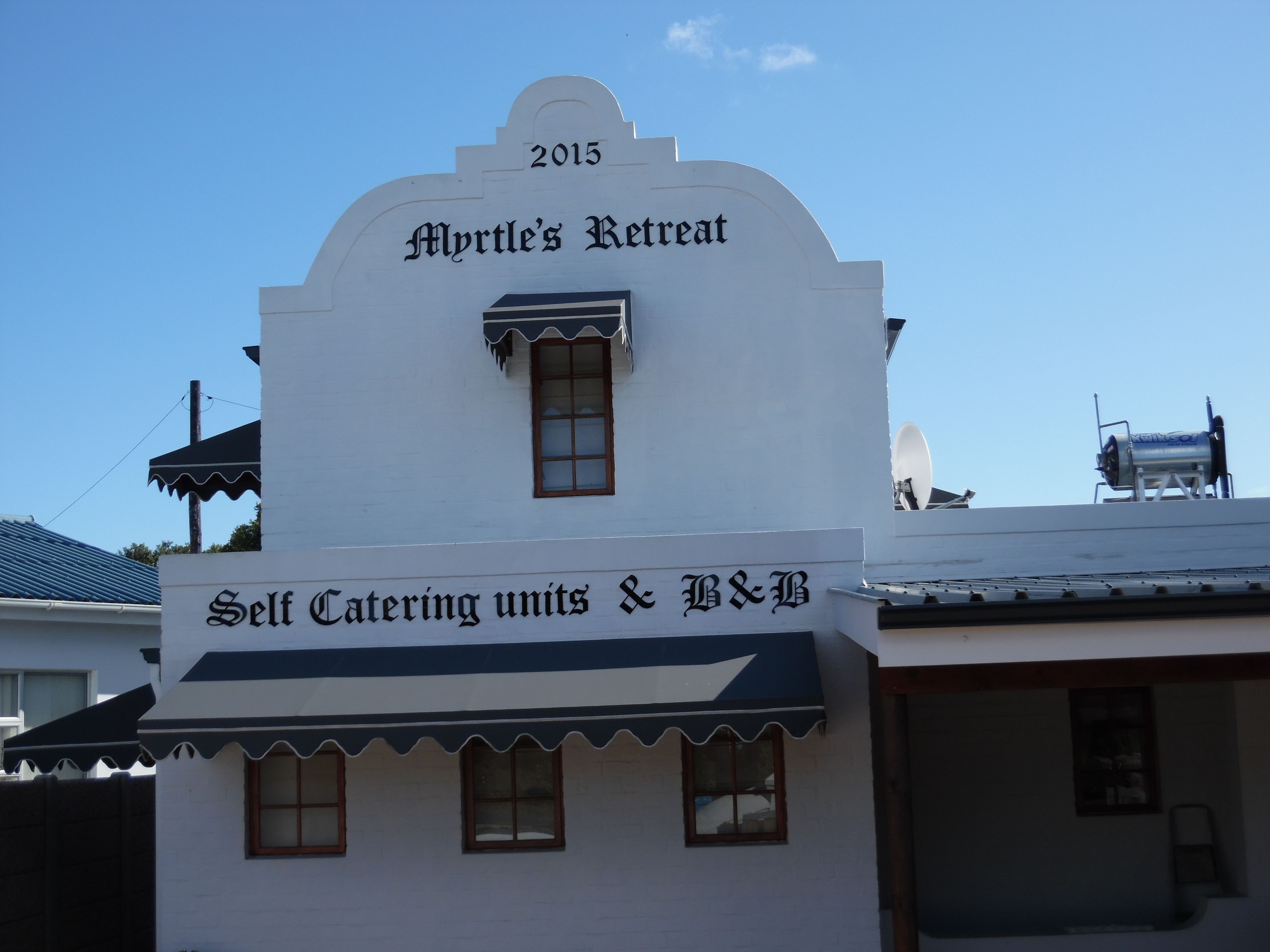 Un edificio con un letrero que dice "Myrtle's Retreat" y "Alojamientos independientes y barbacoa".