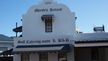 Un edificio con un letrero que dice "Myrtle's Retreat" y "Alojamientos independientes y barbacoa".