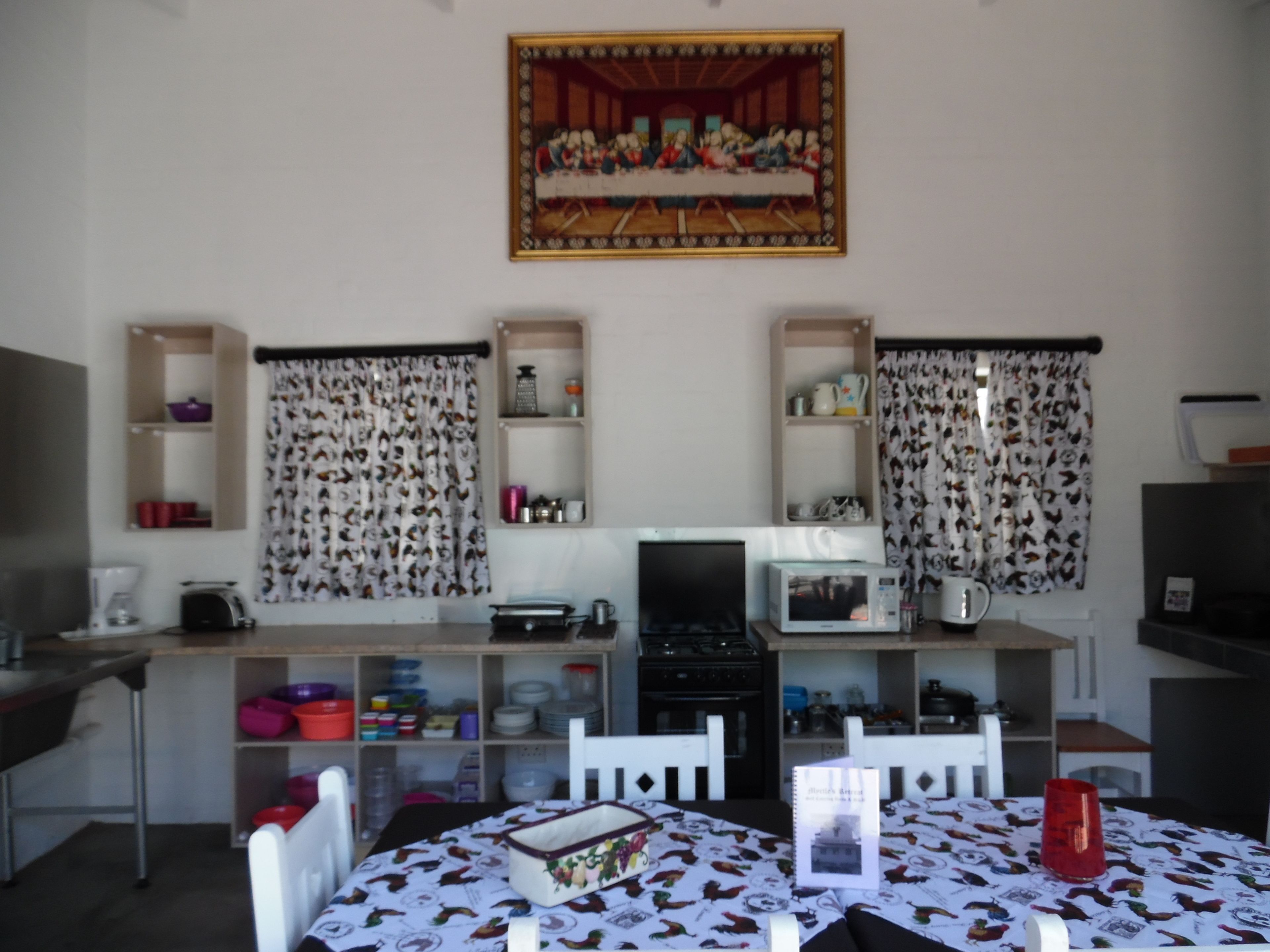 Cocina compacta con una mesa de comedor, sillas, microondas y estufa.