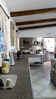 Uma cozinha com bancada de granito, vigas de madeira e diversos eletrodomésticos.