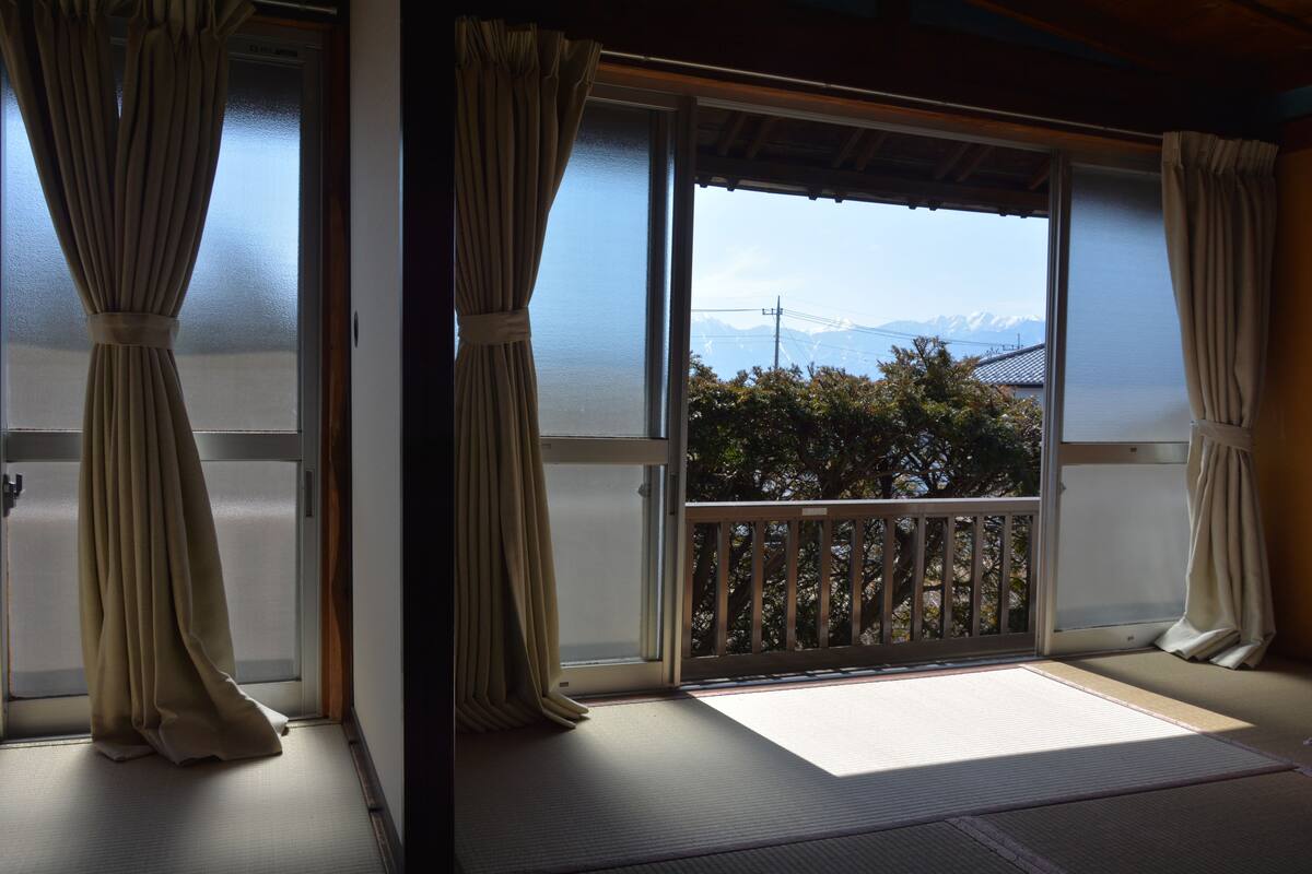 A room with tatami flooring, sliding doors, and a view of mountains.