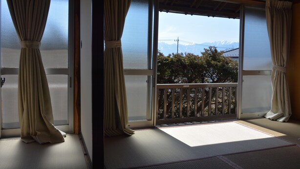 A room with tatami flooring, sliding doors, and a view of mountains.