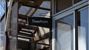 A sign reading "Deerhorn" attached to a wooden structure with a window in the background.